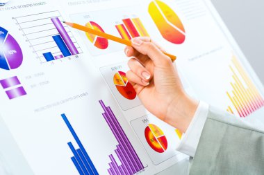 Finansal grafikler üzerinde gösteren bir el