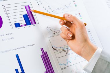 Finansal grafikler üzerinde gösteren bir el