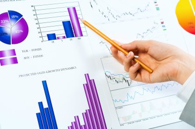 Finansal grafikler üzerinde gösteren bir el