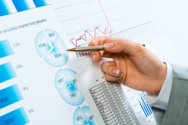 Finansal grafikler üzerinde gösteren bir el