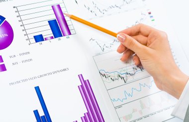 Finansal grafikler üzerinde gösteren bir el