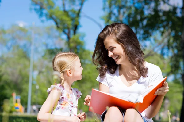 Dívka a mladá žena, společné čtení knihy — Stock fotografie
