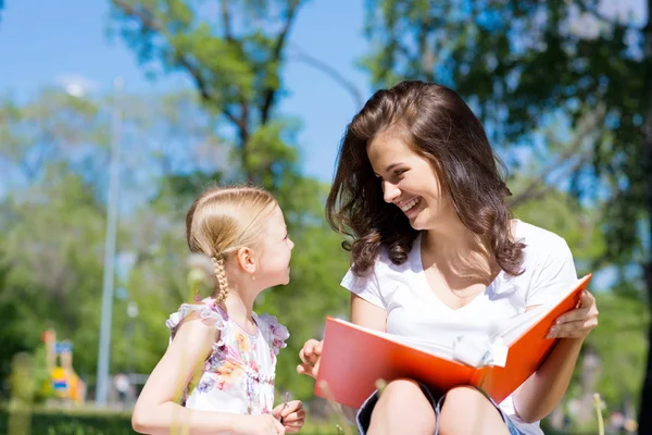 Fille et une jeune femme lisant un livre ensemble — Photo