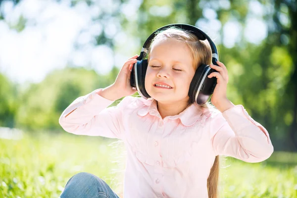 Mädchen im Sommerpark hört Musik — Stockfoto