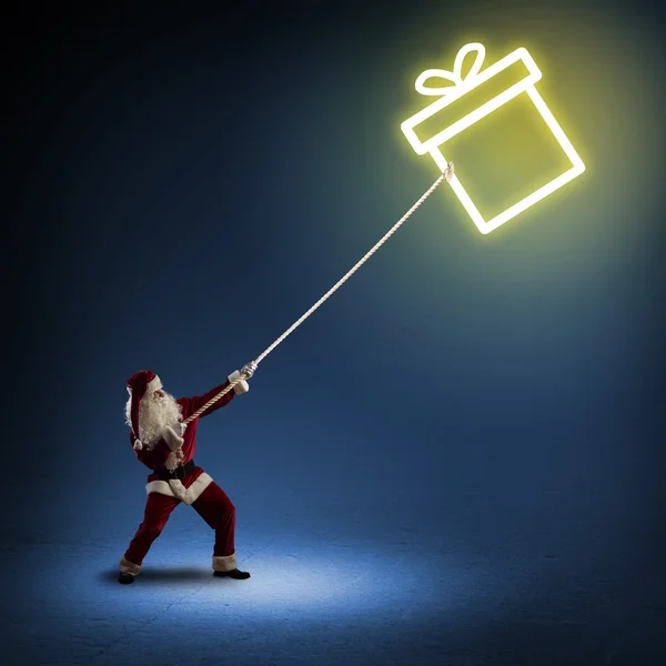 Papai Noel puxa uma caixa com um presente — Fotografia de Stock