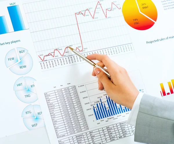 Hand pointing on financial charts — Stock Photo, Image