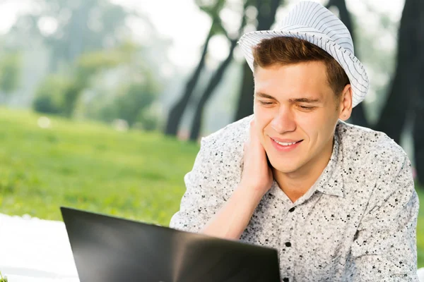 Giovane che lavora nel parco con un computer portatile — Foto Stock