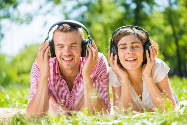 Couple in summer park listening music — Stock Photo, Image