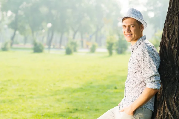 Jonge man leunend tegen boom — Stockfoto