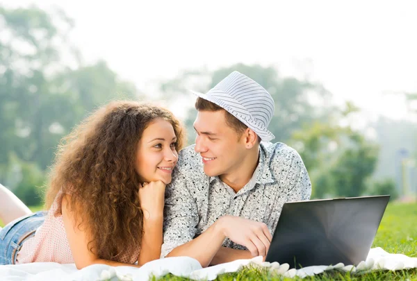 Casal deitado no parque com laptop — Fotografia de Stock