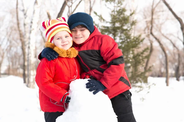 Menino e menina brincando com neve no parque de inverno — Fotografia de Stock