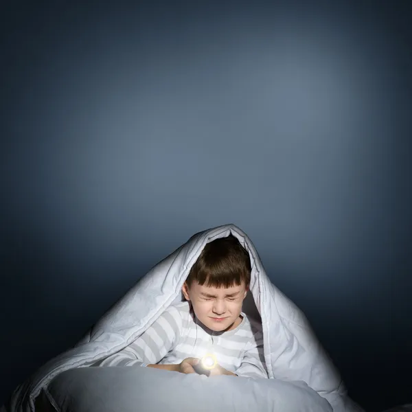 Boy under the covers with a flashlight — Stock Photo, Image