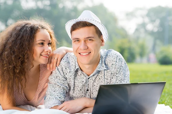 Paar liggen in park met laptop — Stockfoto