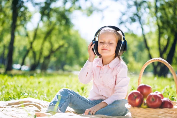Mädchen im Sommerpark hört Musik — Stockfoto
