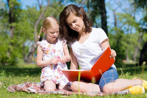 Dziewczyna i młoda kobieta, czytając książkę razem — Zdjęcie stockowe
