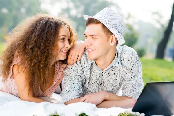 Couple couché ensemble dans un parc avec ordinateur portable — Photo