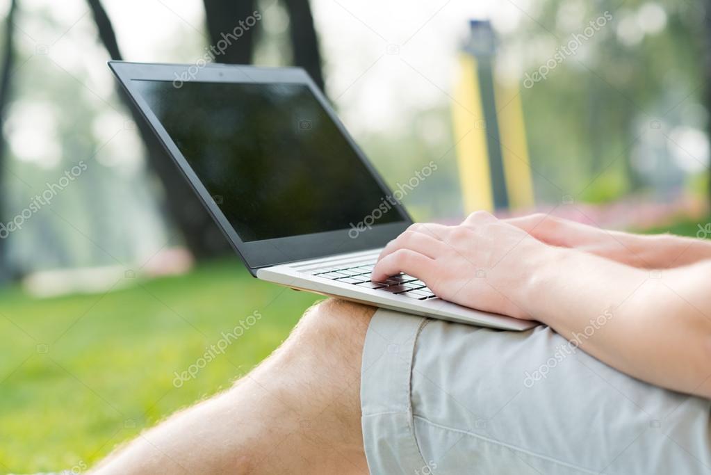 Man working in park with laptop