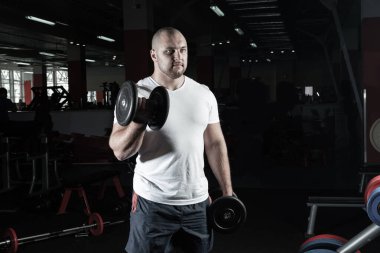 Spor salonunda dambıllarla çarpışan erkek vücut geliştirici.