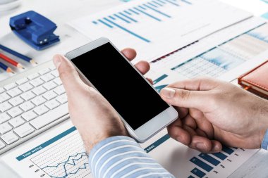 Akıllı telefonlu bir iş adamı, ofiste çalışıyor.