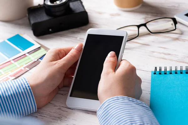 Blogger sentado en el escritorio y sosteniendo el teléfono inteligente —  Fotos de Stock