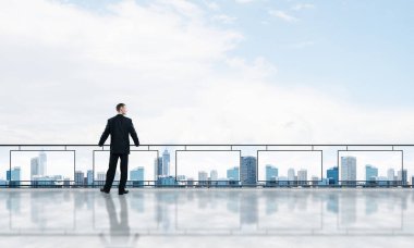 Gökdelenlerin üzerinde gün doğumu ve yeni bir güne bakan iş adamı