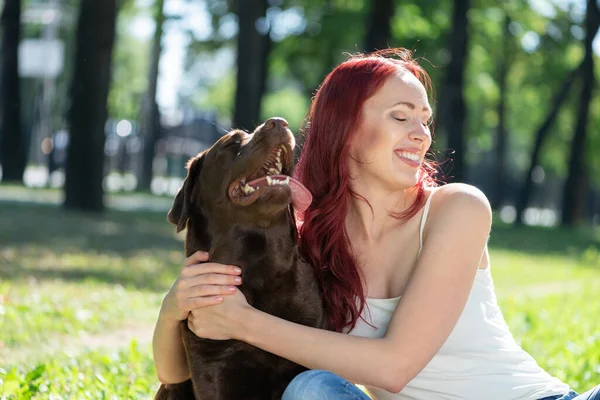 Jovem mulher atraente abraça seu cão no parque. — Fotografia de Stock
