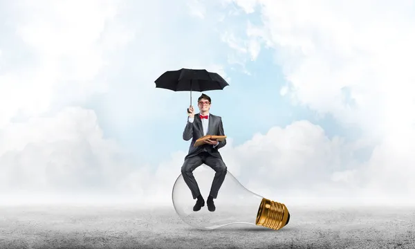 Jovem empresário com um guarda-chuva e um livro — Fotografia de Stock