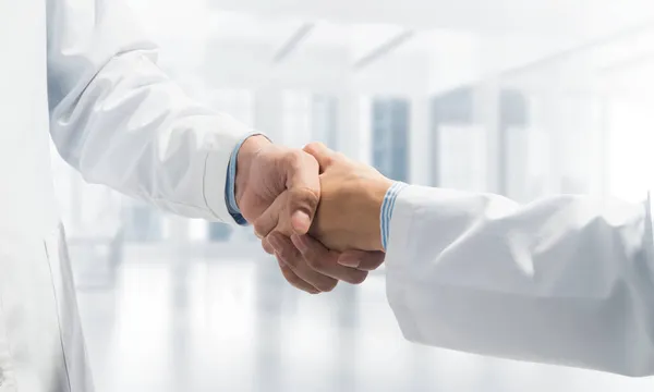 Close-up of the handshake between the two medics. Against the backdrop of the cityscape — Stock Photo, Image