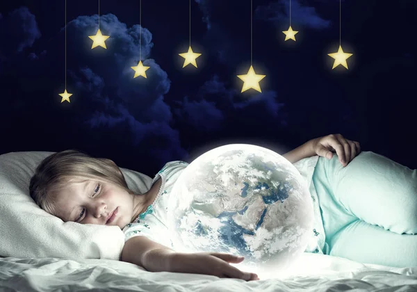 Girl in her bed and glowing globe — Stock Photo, Image