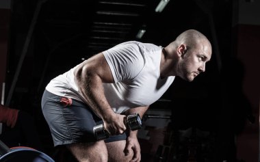 Spor salonunda dambıllarla çarpışan erkek vücut geliştirici.