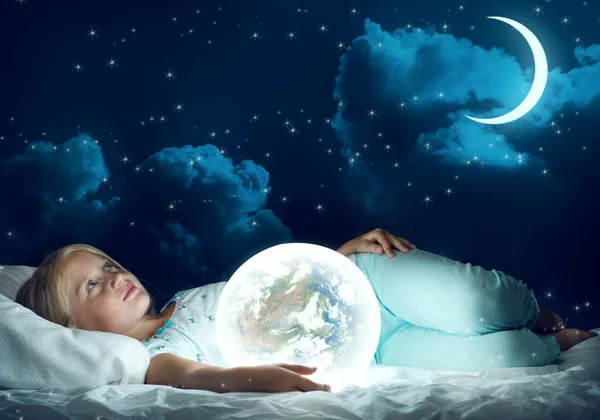 Meisje in haar bed en gloeiende globe — Stockfoto