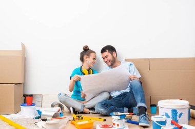 Mutlu çift, elinde planla yerde oturuyor..