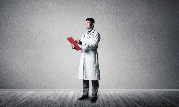 El médico sostiene una tableta roja para documentos delante de él. — Foto de Stock