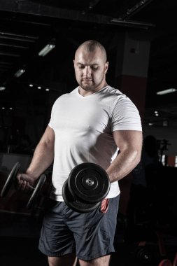 Spor salonunda dambıllarla çarpışan erkek vücut geliştirici.