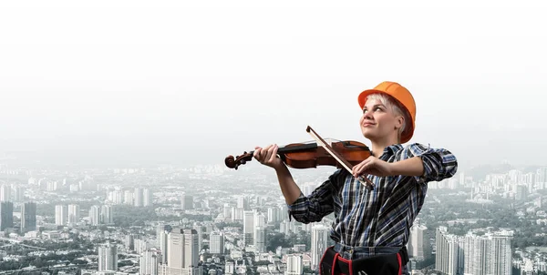 Belle femme en casque de sécurité jouant du violon — Photo