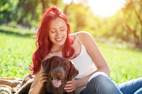 Jovem mulher atraente abraça seu cão no parque. — Fotografia de Stock