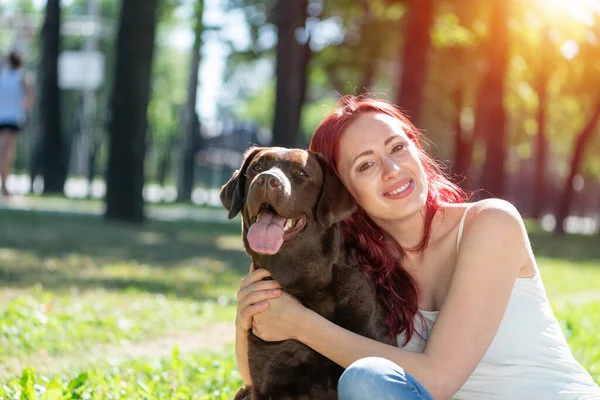 Junge attraktive Frau umarmt ihren Hund im Park. — Stockfoto