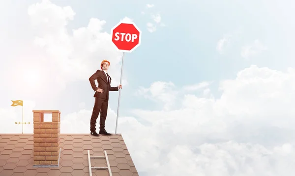 Καυκάσιος επιχειρηματία σε στέγη σπιτιού τούβλα δείχνει πινακίδα stop. Μικτή τεχνική — Φωτογραφία Αρχείου