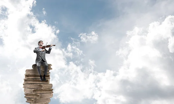 Bellissimo violinista in cielo blu giorno su mucchio di libri suonare la sua melodia — Foto Stock