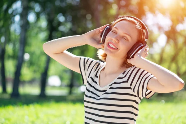 Une jeune femme a de la musique dans un parc d'été. — Photo