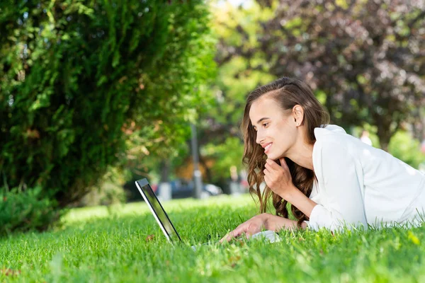 Ung kvinna och bärbar dator i parken — Stockfoto