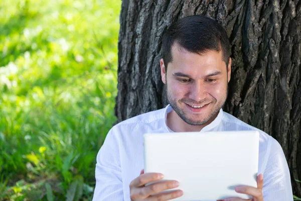 Homme utilisant un ordinateur tablette sous l'arbre dans le parc — Photo