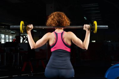 Vücut geliştiren kadın, spor salonunda halterle bağlanmış.