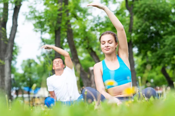 Giovane coppia che fa yoga nel parco insieme — Foto Stock