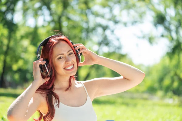 A fiatal nőnek történetesen van zenéje egy nyári parkban. — Stock Fotó