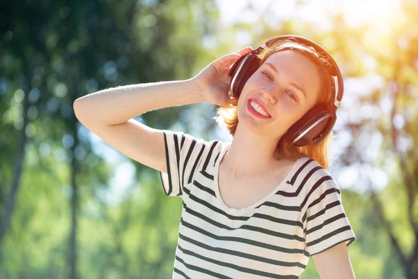 У молодой женщины есть музыка в летнем парке. — стоковое фото