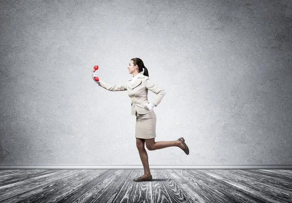 Woman running in room with vintage red phone — 图库照片