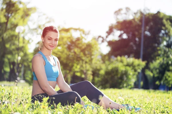 Krásná usměvavá dívka ve sportovním oblečení relaxovat v parku — Stock fotografie