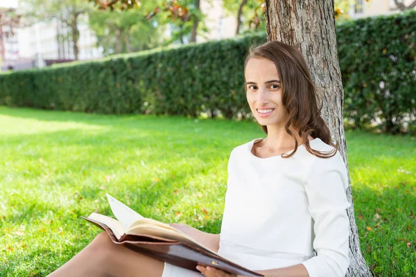 Schöne junge Frau mit Notizblock im Park — Stockfoto