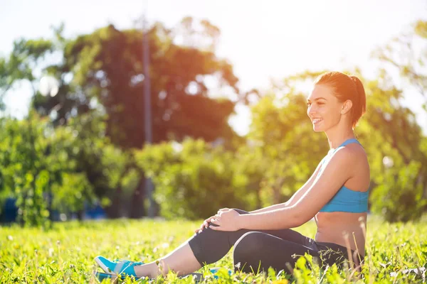 Mooi glimlachend meisje in sportkleding ontspannen in park — Stockfoto